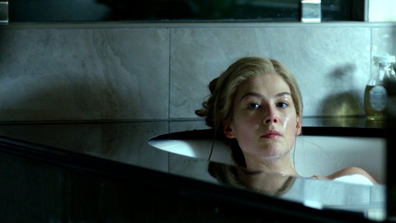 Rosamund Pike, sitting in a bathtub, looking introspectively off into the distance