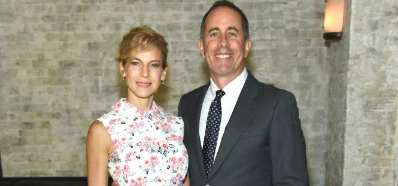 Jerry and Jessica Seinfeld take a picture together in front of a brick wall.