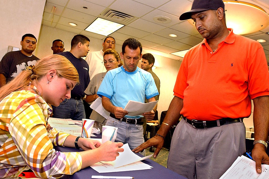 A man stands in line with other applicants as they wait for interview appointments