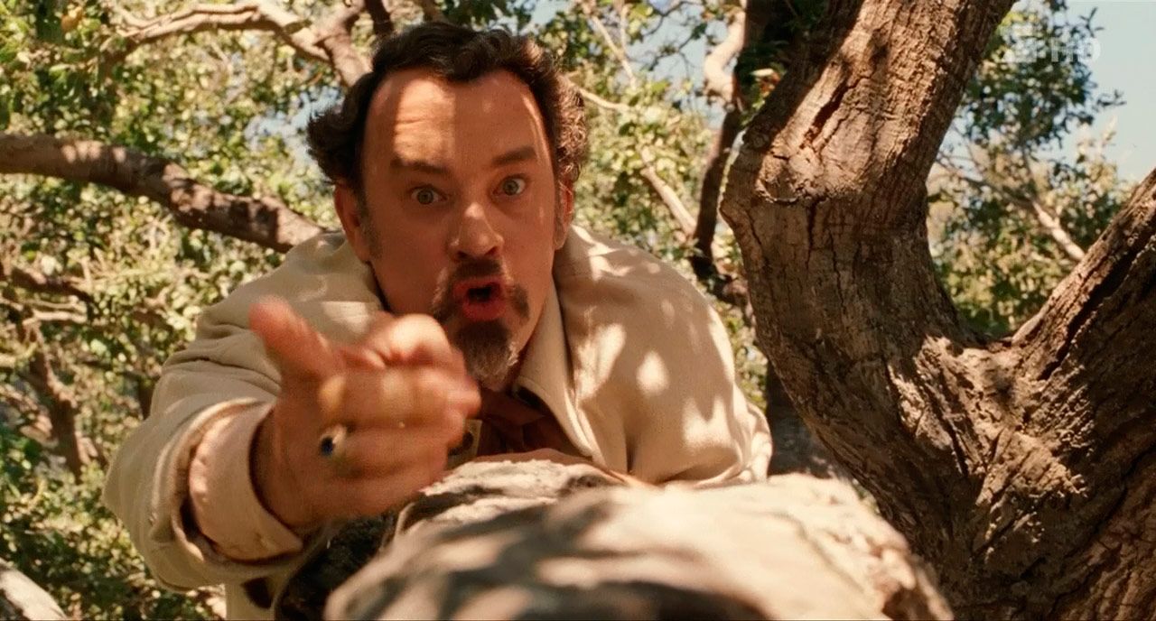 Tom Hanks points upwards while climbing a tree in The Ladykillers