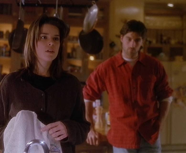 Julia doing dishes in the kitchen looking surprised as Charlie stands behind her