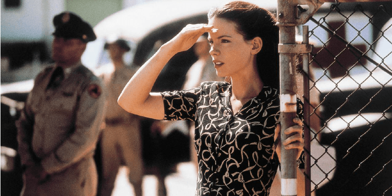 Kate Beckinsale is a dress and covering her eyes as she looks out.