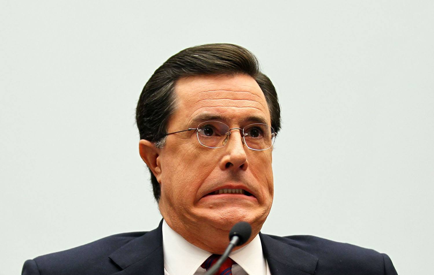 Stephen Colbert makes a face while talking into a mic