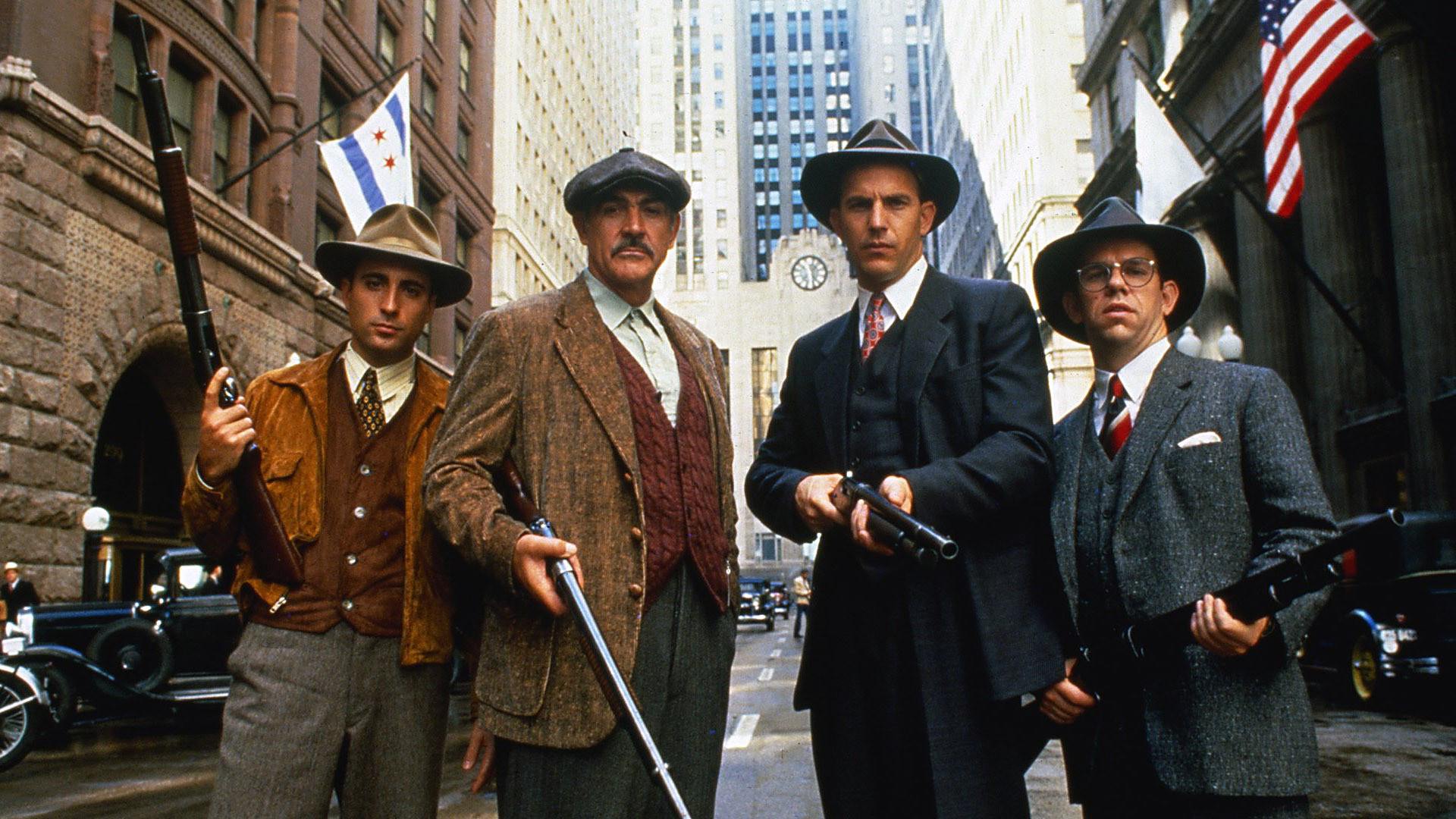The cast of the Untouchables, posing in a city street and wielding various guns