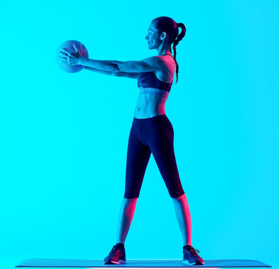 one mixed races woman exercsing Medicine Ball fitness exercices isolated on blue blackground