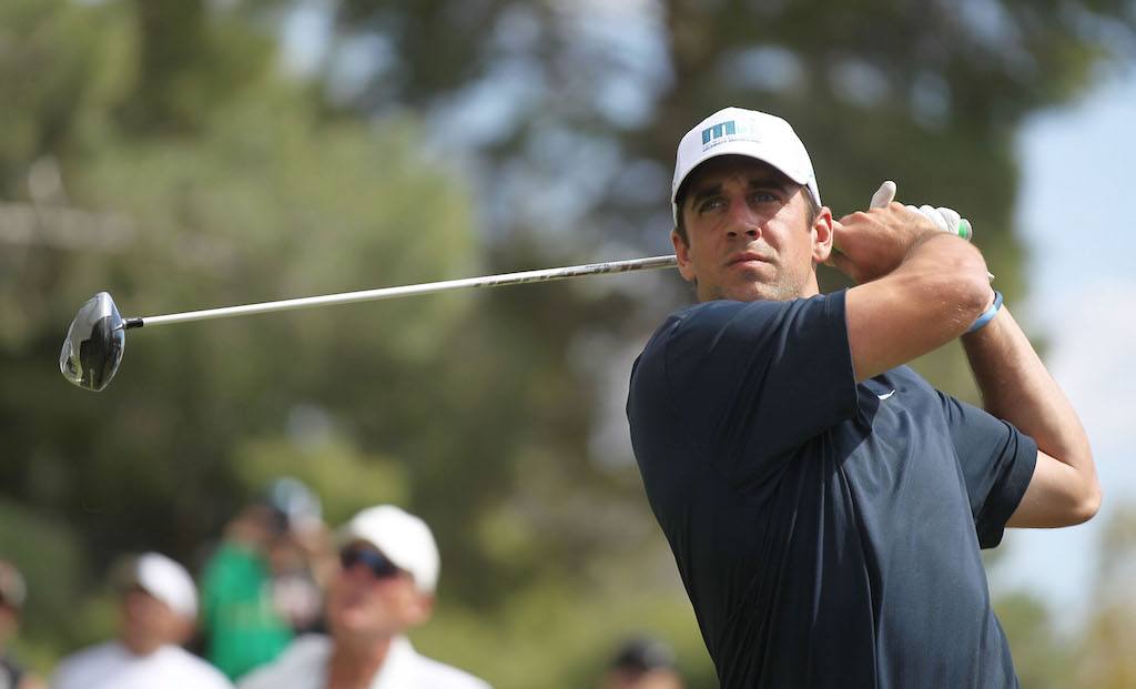 Aaron Rodgers hits a shot on a golf course. Aaron Rodgers hits a shot on a golf course.