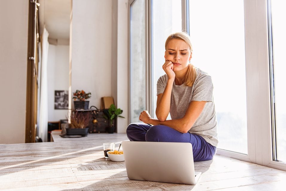 woman sitting on the floor Woman sitting on floor near window and watching laptop