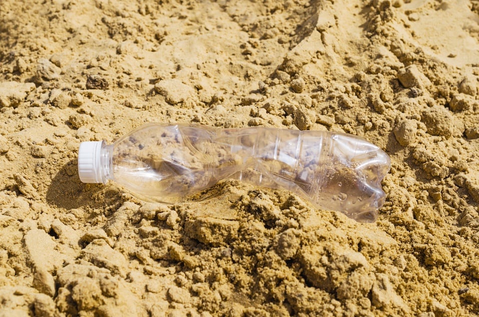 Empty crumpled plastic bottle of water abandoned on the beach