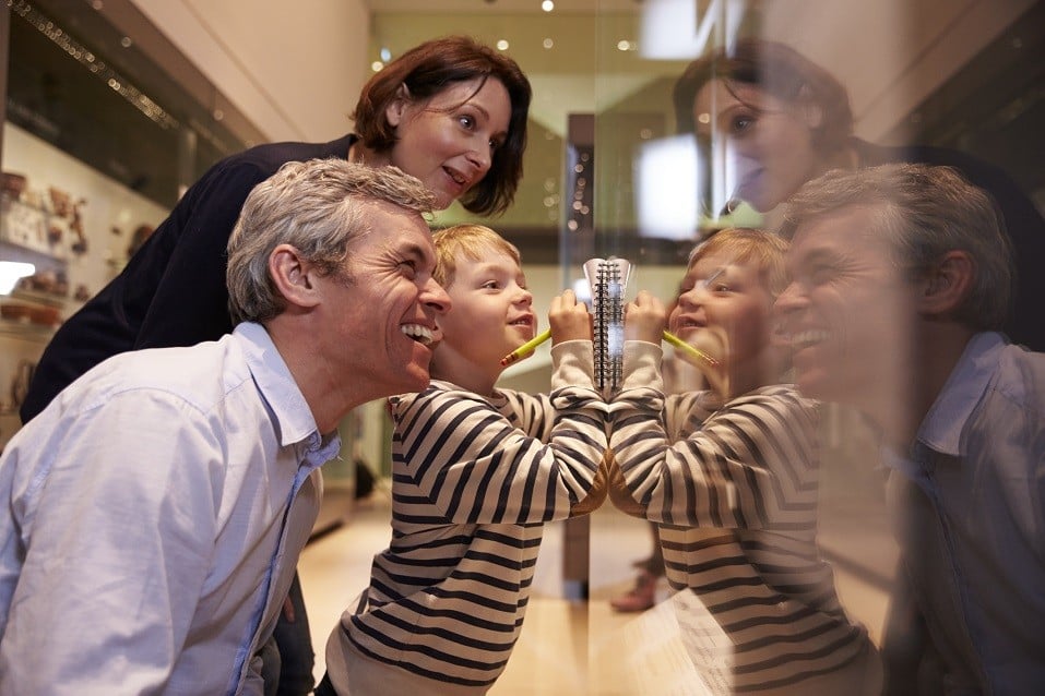 Family Looking At Artifacts In Glass Case On Trip