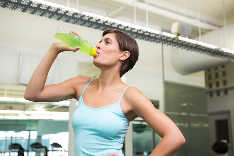 Fit brunette drinking energy drink at the gym