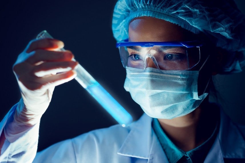 Medical researcher holding test tube with blue fluorescent liquid. Medical researcher holding test tube