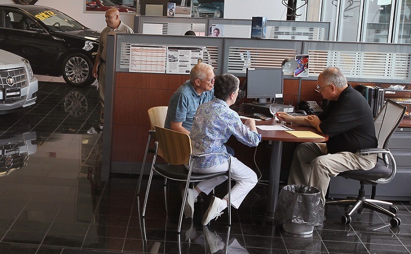 LINCOLNWOOD, IL - AUGUST 30: Salesman Gus Donas (R) finishes the deal on a Buick Enclave being purchased by Bob and Carrol Welch at the Grossinger Autoplex car dealership August 30, 2010 in Lincolnwood, Illinois. A strong demand for automobiles helped to drive consumer spending in July to its strongest pace in four months.