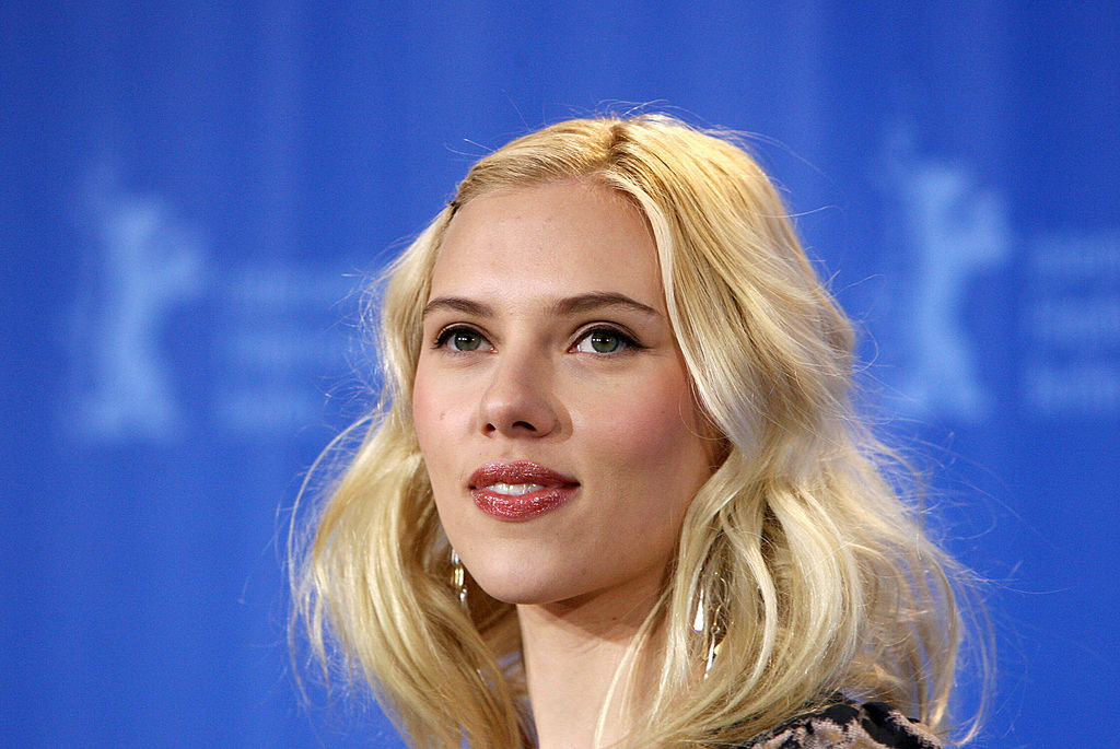 Scarlett Johansson stands in front of a blue background. 