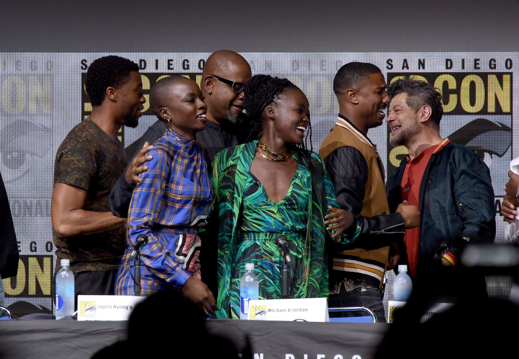 Black Panther cast members smiling and embracing on stage at Comic-Con
