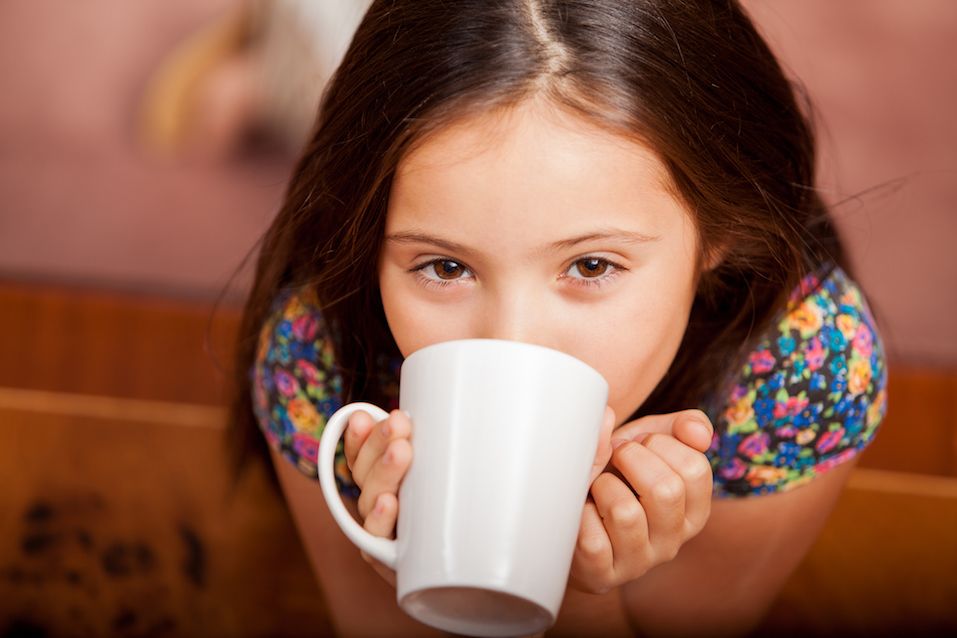 Happy little girl enjoying a cup of hot chocolate at home