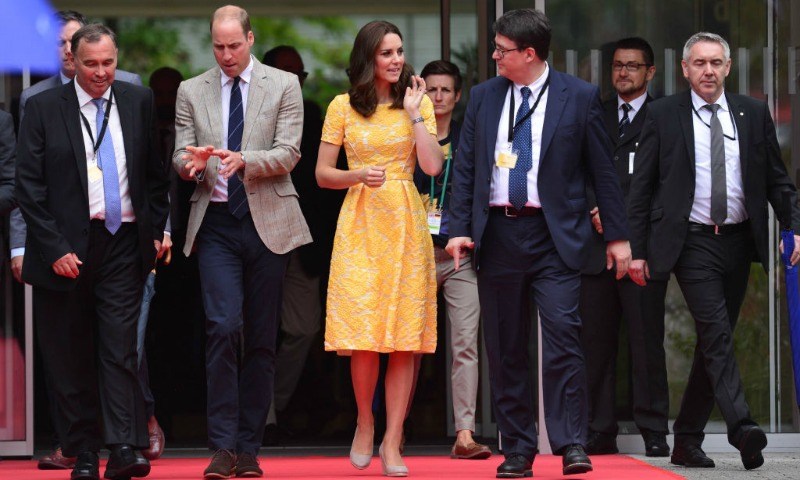Kate Middleton and Prince William are walking alongside men in suits on a red carpet. Kate Middleton and Prince William are walking alongside men in suits on a red carpet.