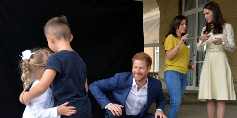 Kate Middleton is talking to a woman as Prince Harry watches two kids hug. Kate Middleton is talking to a woman as Prince Harry watches two kids hug.