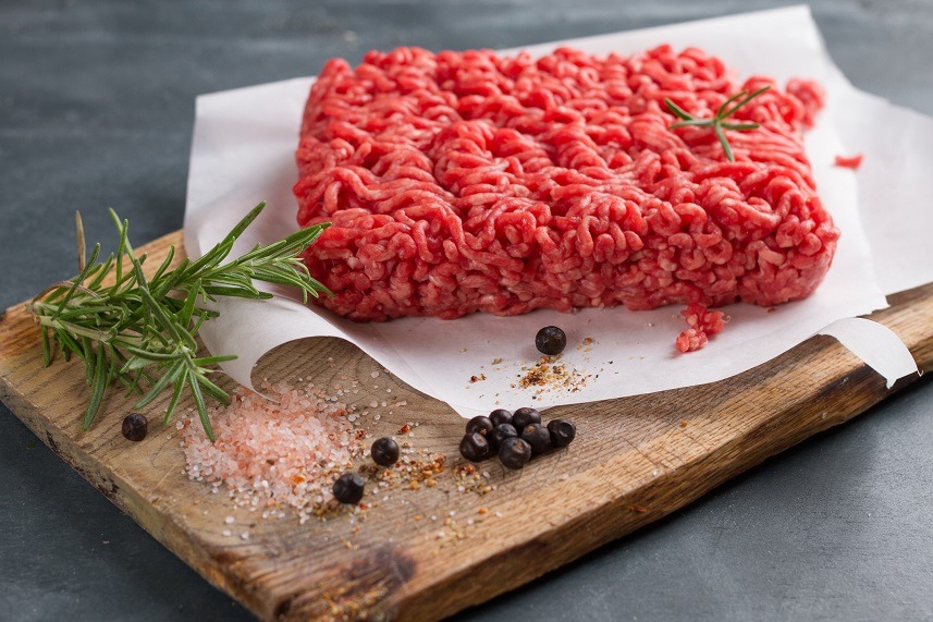 Minced red meat on butcher paper with basil