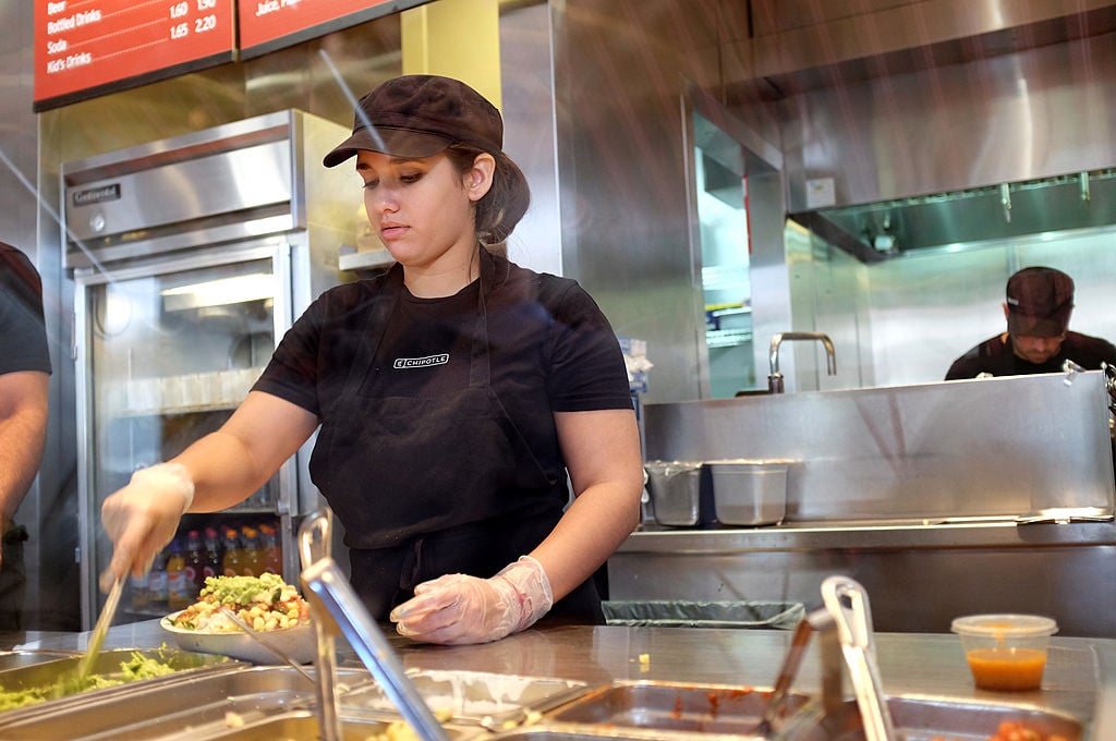 A restaurant worker uses a spoon to get Guacamole