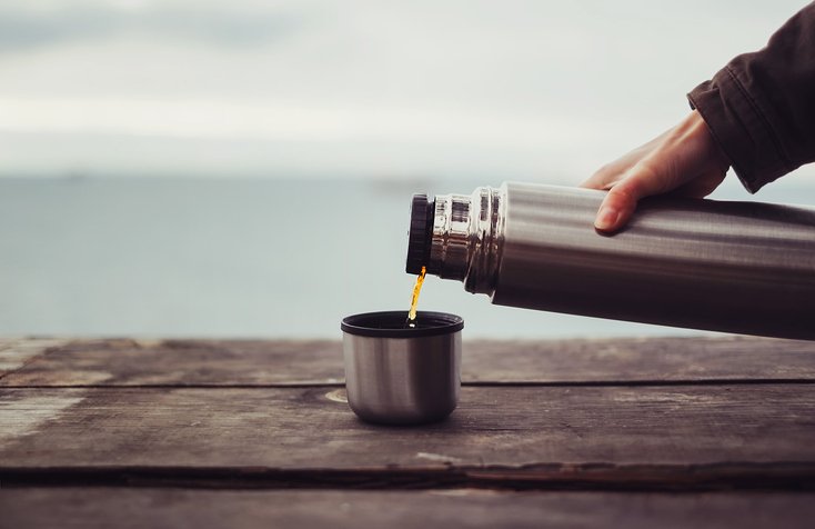 Traveler pouring tea from thermos
