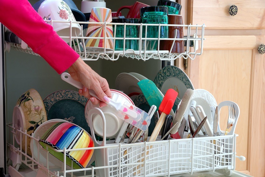 A female hand is shown loading dishes