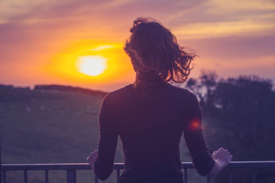 Woman admiring sunset from her balcony Woman admiring sunset from her balcony