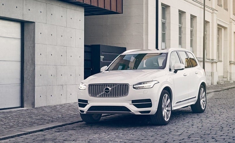 Fron three quarter view of white Volvo XC90 outside a garage