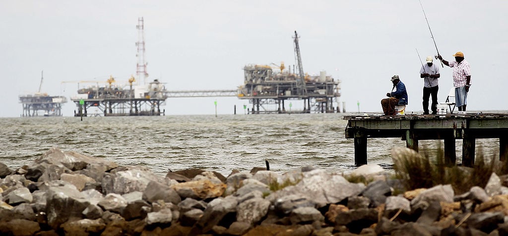 People fish near an oil rig on the Alabama coast