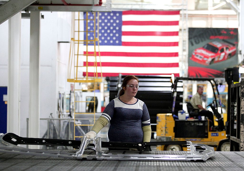 A worker handles parts for Fiat Chrysler Automobiles as they come off the press