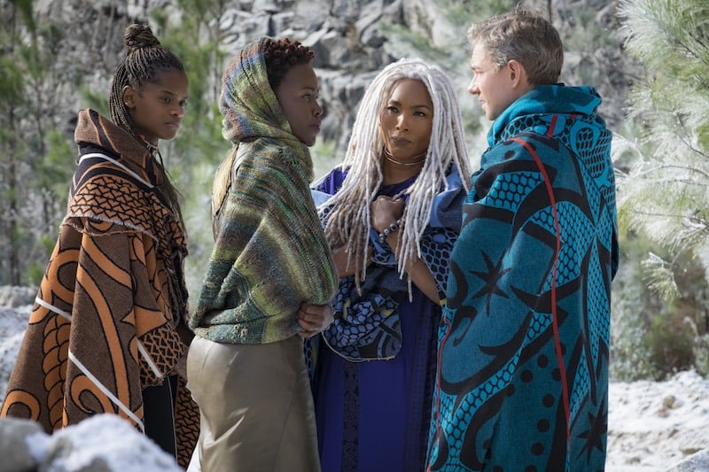 A trio of women in shawls talk with a man in Black Panther