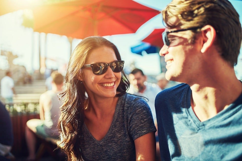 happy dating couple at outdoor restaurant with lens flare