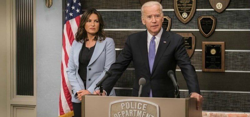 Joe Biden is speaking at a podium beside Mariska Hargitay.