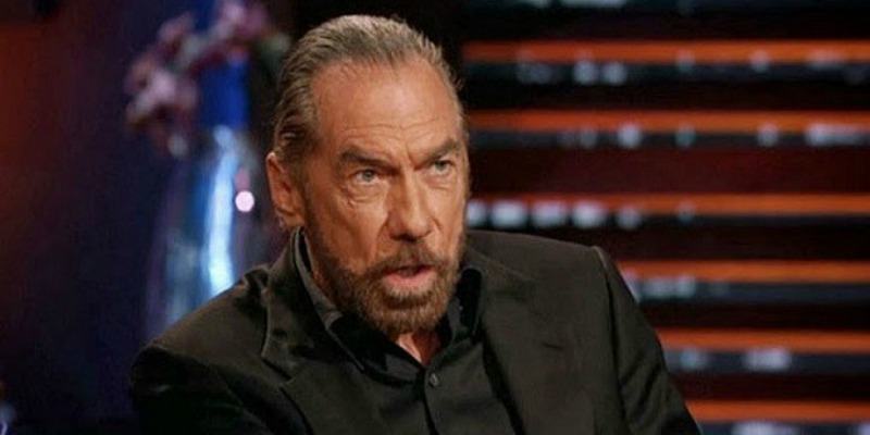 John Paul DeJoria is talking while sitting down on Shark Tank.