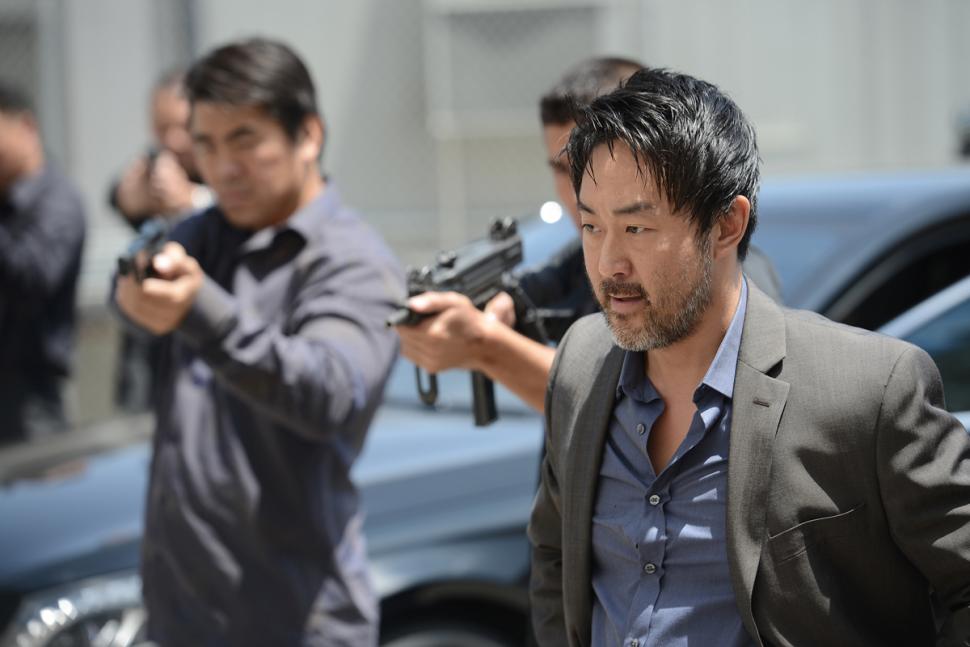 Kenneth Choi stands by men holding guns