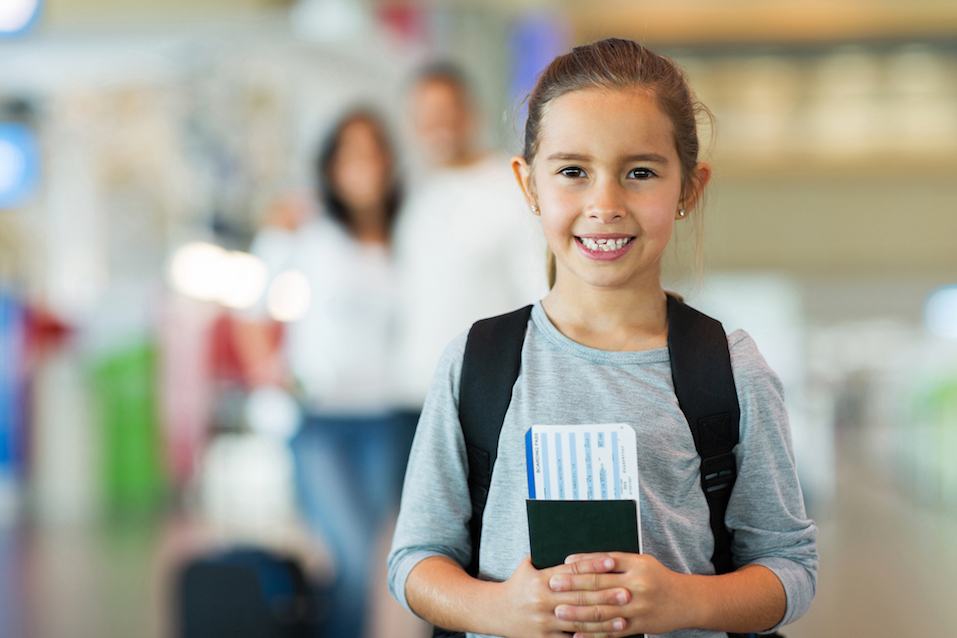 beautiful little girl holding passport and boarding pass
