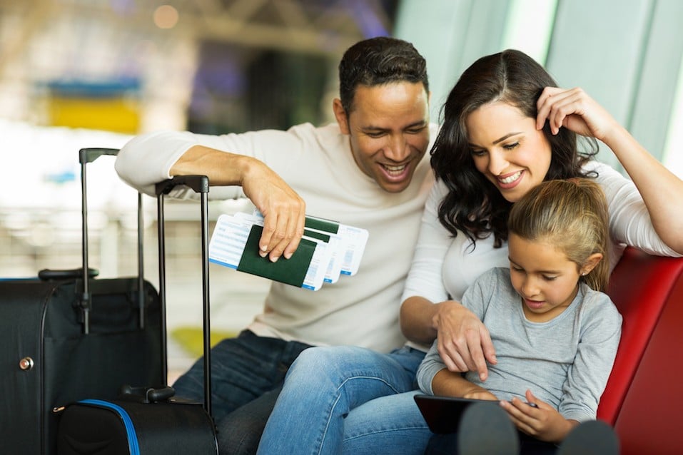 little girl using tablet pc with parents at airport