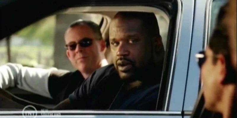 Shaq is in a cop car looking out the window in Southlands.