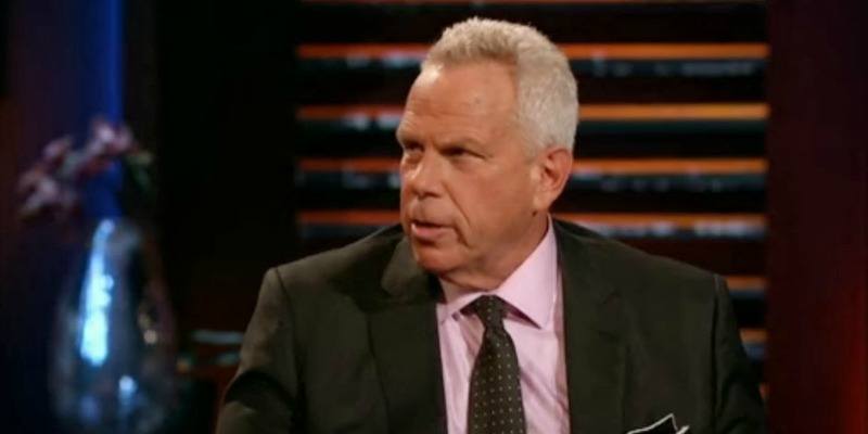 Steve Tisch is seated and looking to the side on Shark Tank.