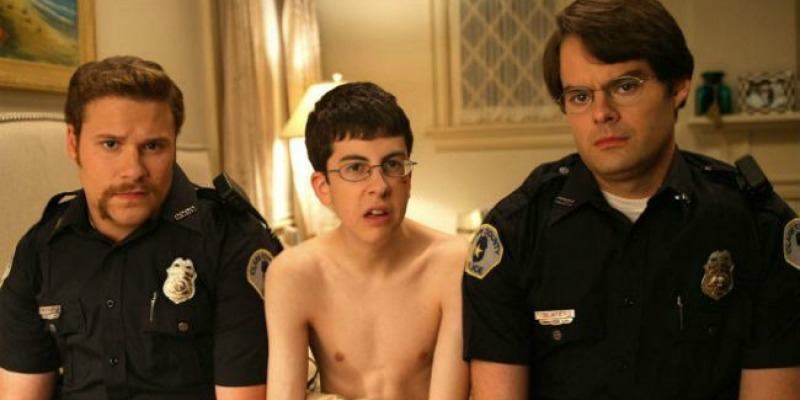 McLovin is sitting in just a towel around his waist between two police officers. McLovin is sitting in just a towel around his waist between two police officers.