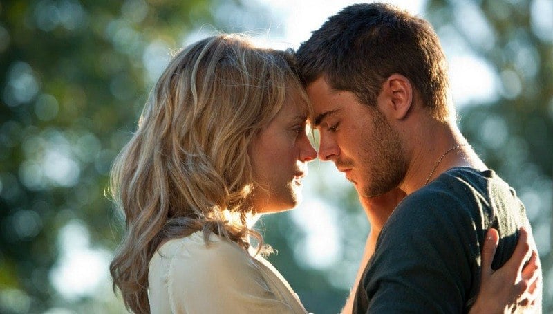 Zac Efron and Taylor Schilling are leaning their heads against each other as they're about to kiss. Zac Efron and Taylor Schilling are leaning their heads against each other as they're about to kiss.