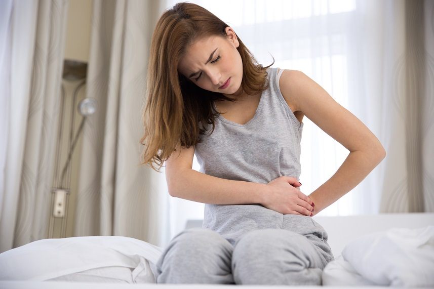 Woman sitting up in bed in pain Woman sitting up in bed in pain