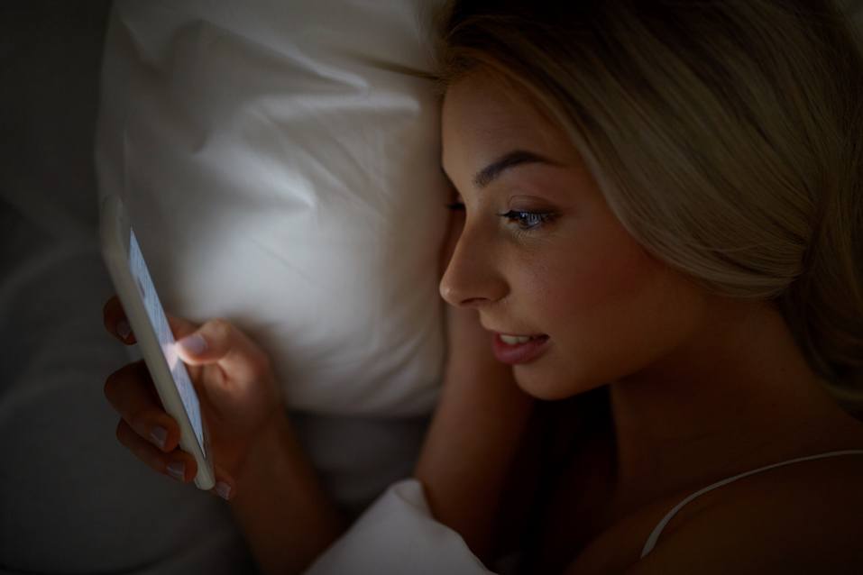 young woman texting on smartphone in bed young woman texting on smartphone in bed