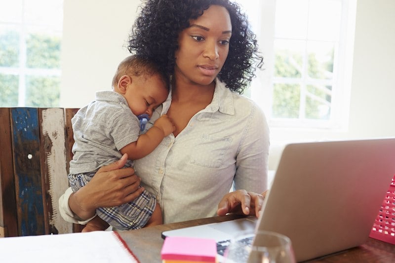 A woman working with her child in her arms A woman working with her child in her arms