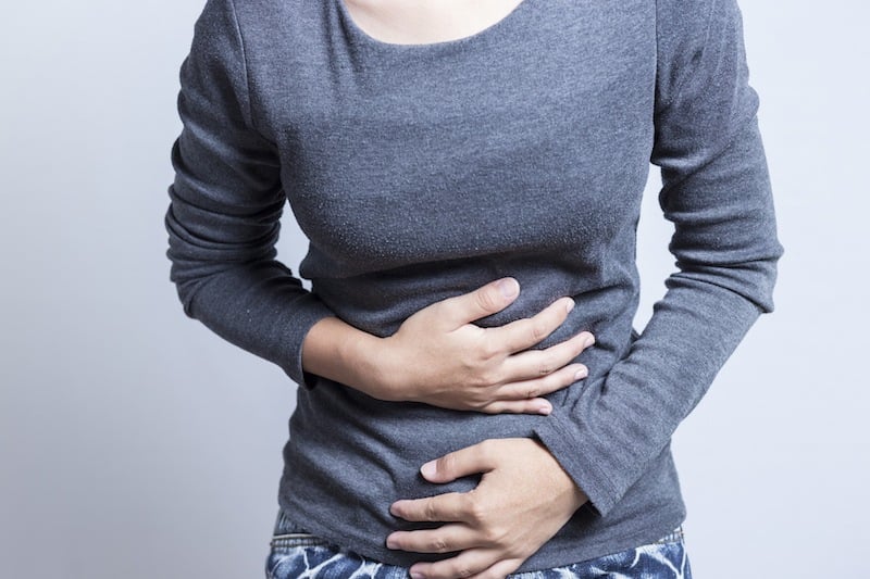 woman with a stomachache clutching her stomach woman with a stomachache clutching her stomach