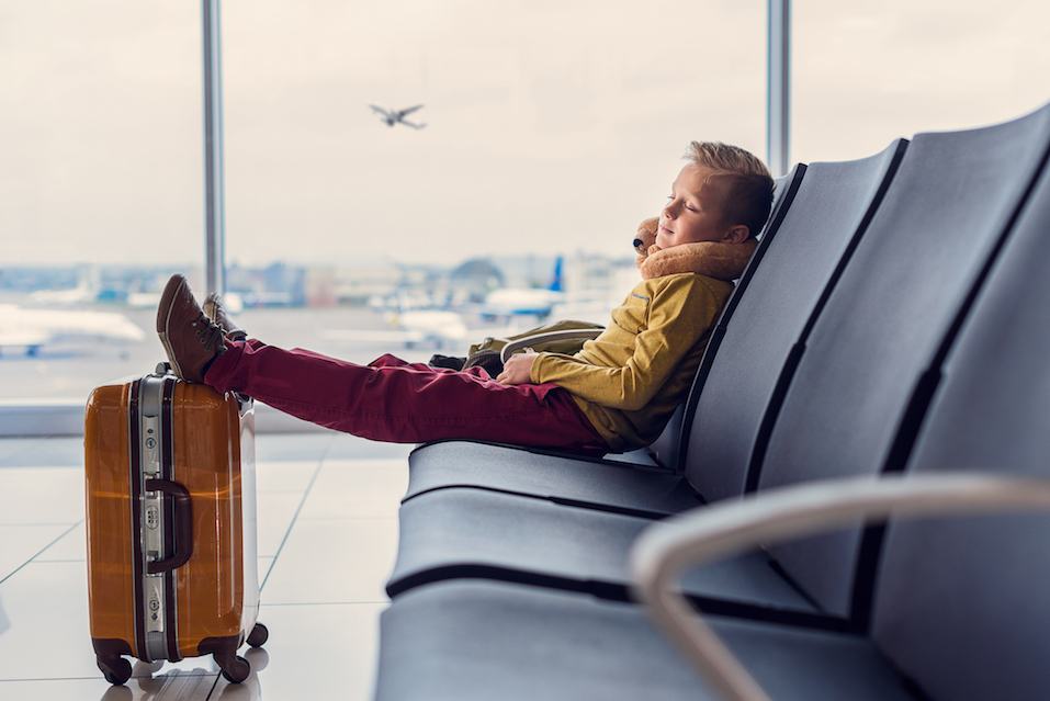 Little boy sleeping while sitting in airport lounge