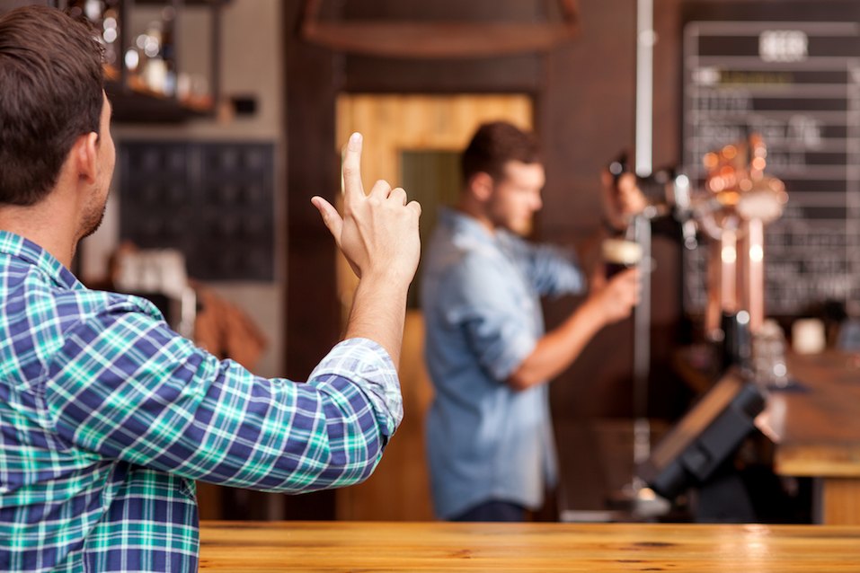 Cheerful man is ordering beer in bar