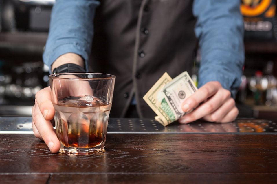 Barman giving whiskey glass with booze
