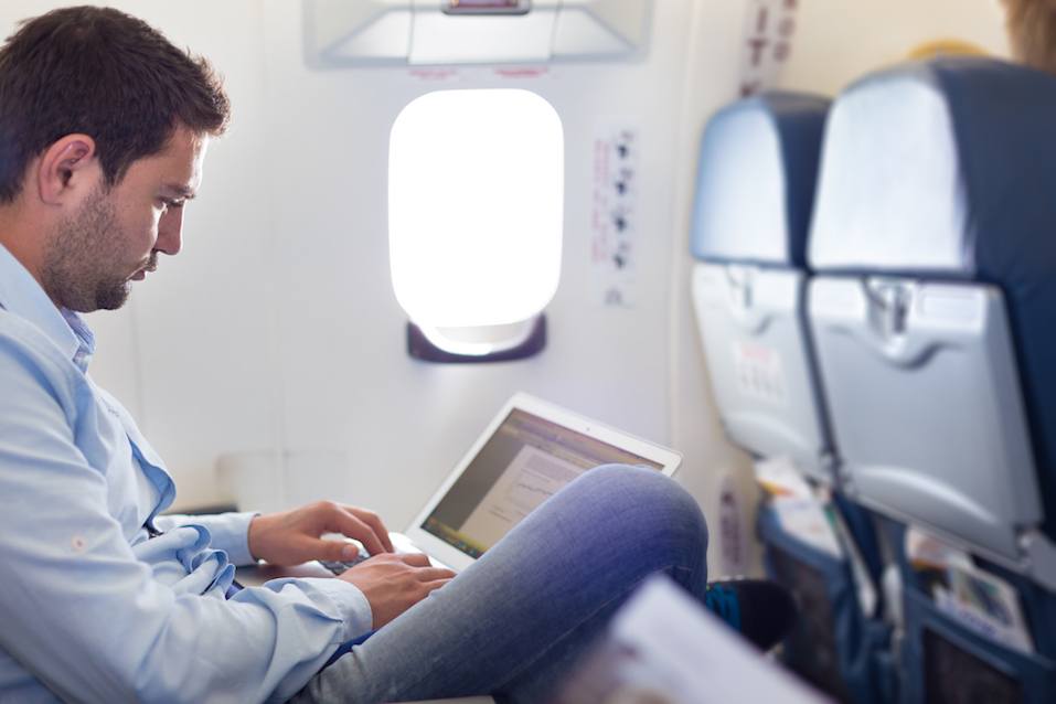 Casually dressed middle aged man working on laptop in aircraft cabin