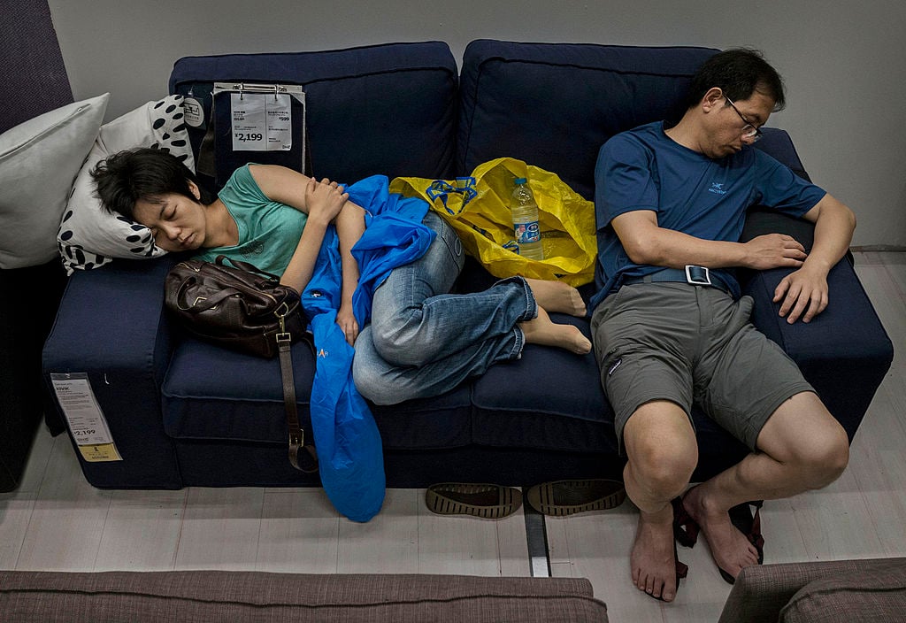Chinese shoppers sleep on a sofa in the showroom of the IKEA store