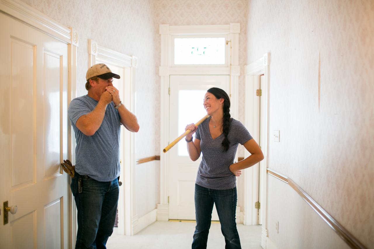 Chip and Joanna Gaines stand in a hallway while laughing. Chip and Joanna Gaines stand in a hallway while laughing.
